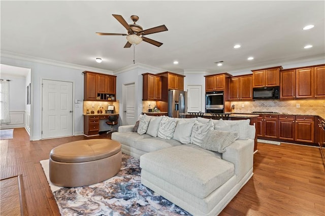 living area with wood finished floors, recessed lighting, ceiling fan, wainscoting, and crown molding