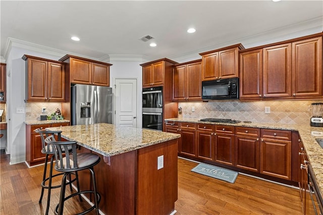 kitchen with visible vents, dark wood-type flooring, a kitchen island, and black appliances