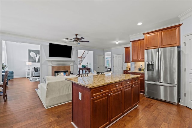 kitchen featuring a glass covered fireplace, dark wood-type flooring, ornamental molding, and stainless steel fridge with ice dispenser