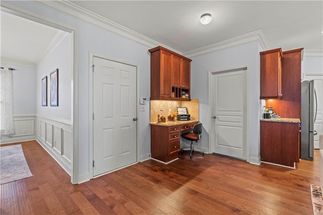 kitchen with dark wood finished floors, decorative backsplash, freestanding refrigerator, and ornamental molding