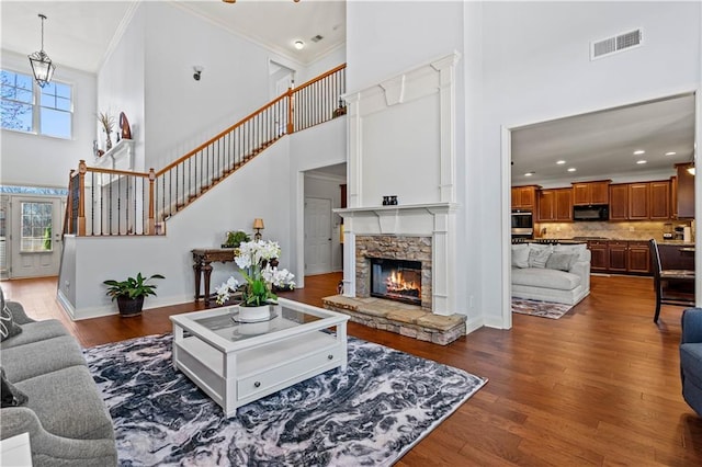 living area featuring visible vents, ornamental molding, plenty of natural light, and dark wood-style flooring