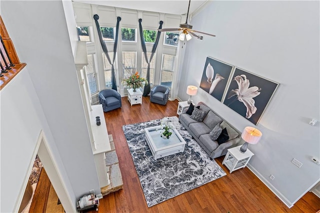 living room featuring ceiling fan, baseboards, and wood finished floors