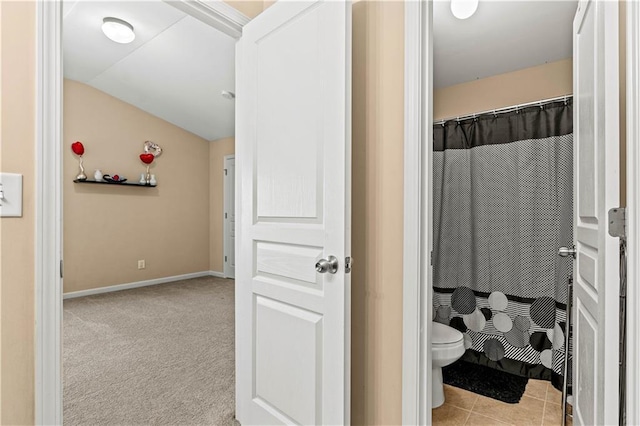 bathroom featuring baseboards, toilet, a shower with shower curtain, lofted ceiling, and tile patterned floors