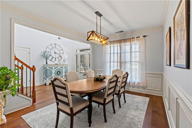 dining area with visible vents, wood finished floors, crown molding, and stairway