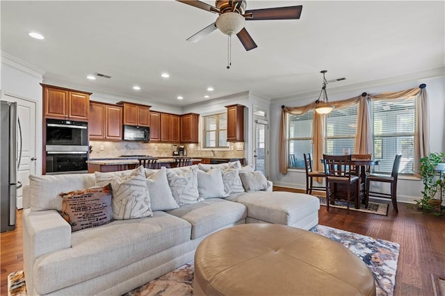 living area with visible vents, baseboards, ornamental molding, and dark wood-style flooring