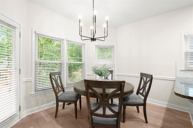 dining space with a chandelier, wood finished floors, baseboards, and healthy amount of natural light
