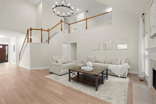 living room with wood finished floors, stairway, a chandelier, a towering ceiling, and baseboards