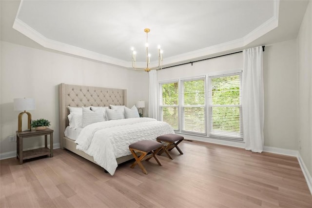 bedroom featuring a tray ceiling, a chandelier, ornamental molding, and light wood finished floors