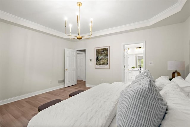 bedroom featuring a chandelier, wood finished floors, ornamental molding, baseboards, and a raised ceiling