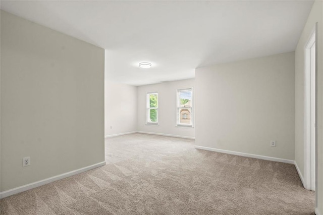 carpeted spare room featuring baseboards