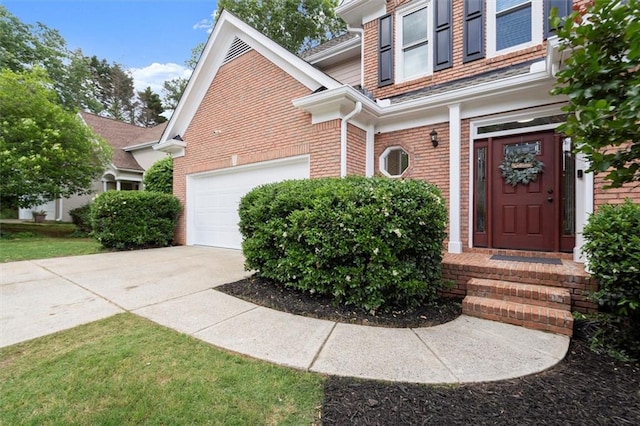 view of exterior entry featuring concrete driveway, brick siding, and a garage