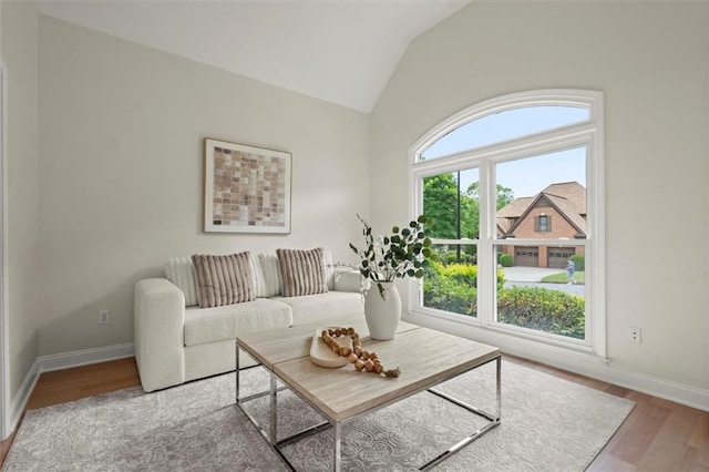 living area with vaulted ceiling, wood finished floors, and baseboards
