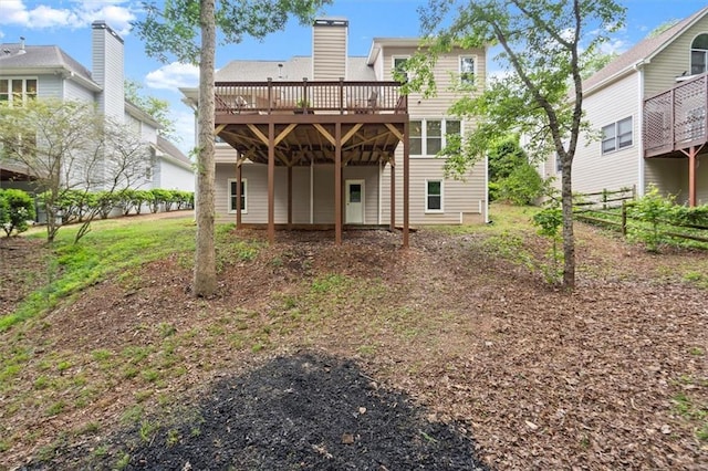 back of house with a deck, a chimney, and fence