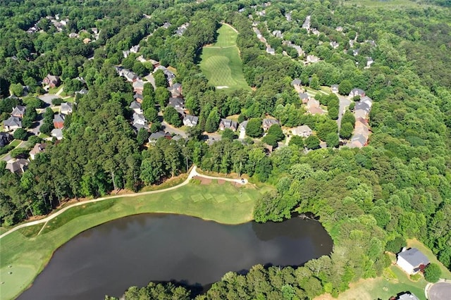 aerial overview of property's location featuring a nearby body of water, a golf course, and a heavily wooded area