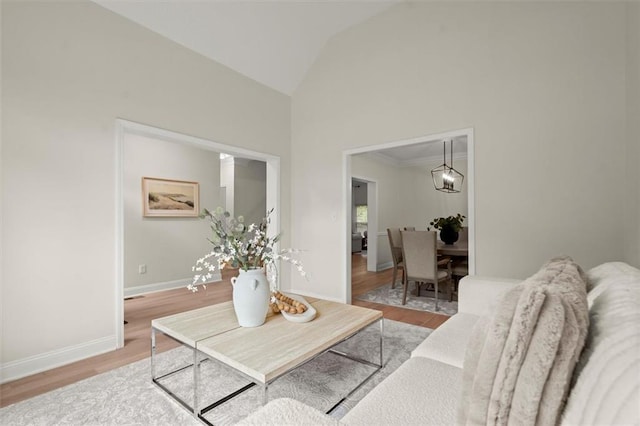 living area featuring wood finished floors, baseboards, and high vaulted ceiling