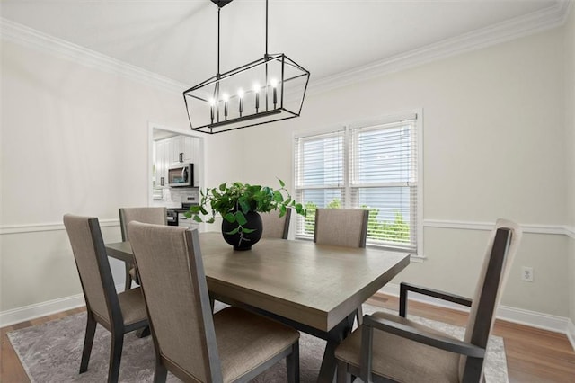 dining room featuring wood finished floors, a chandelier, crown molding, and baseboards