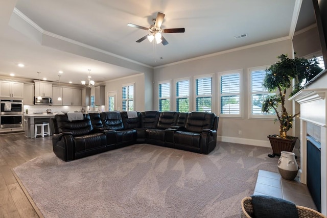 living room with a tiled fireplace, crown molding, ceiling fan with notable chandelier, and light hardwood / wood-style flooring