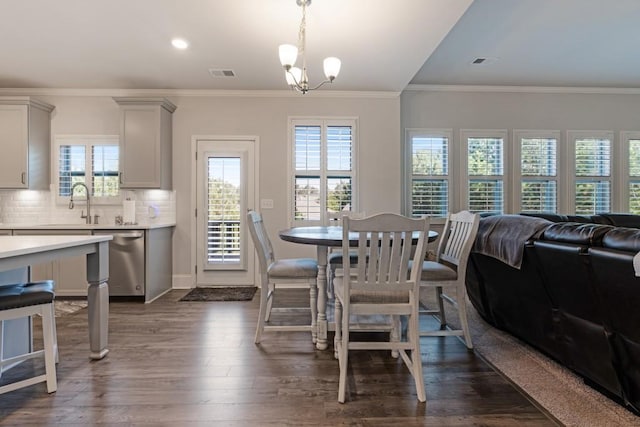 dining room with crown molding, dark wood-type flooring, sink, and an inviting chandelier