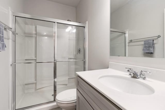 bathroom with a shower with door, vanity, and toilet