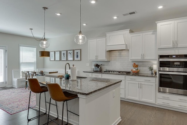 kitchen with backsplash, visible vents, appliances with stainless steel finishes, a sink, and white cabinetry