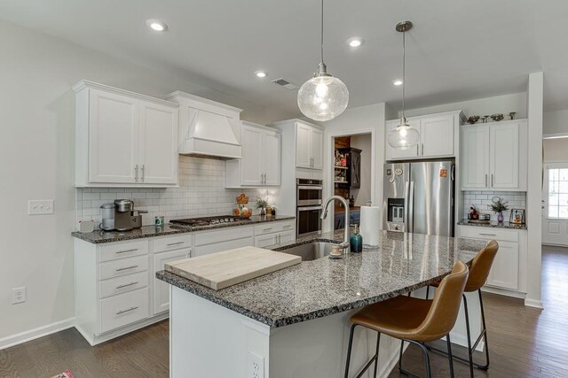 kitchen featuring backsplash, dark wood finished floors, custom range hood, a sink, and stainless steel appliances
