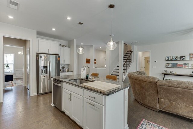 kitchen featuring visible vents, open floor plan, an island with sink, dark wood-type flooring, and stainless steel appliances