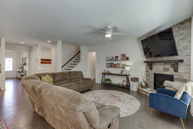 living area featuring stairway, ceiling fan, a fireplace, and wood finished floors