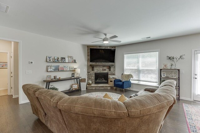 living area with ceiling fan, visible vents, a stone fireplace, and baseboards
