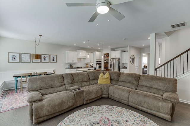 living area featuring a ceiling fan, visible vents, dark wood finished floors, stairs, and recessed lighting