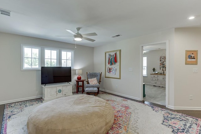 living area with visible vents, a ceiling fan, and baseboards