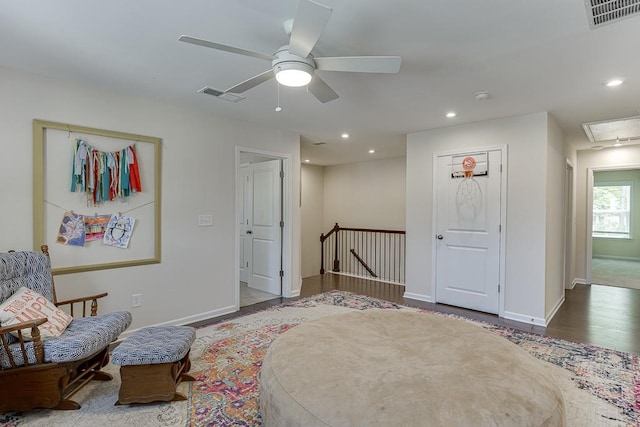 living area featuring visible vents, attic access, ceiling fan, and an upstairs landing