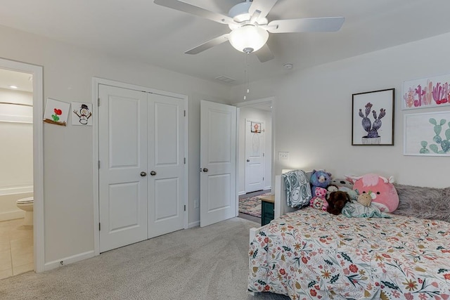 carpeted bedroom with a closet, a ceiling fan, baseboards, and ensuite bathroom