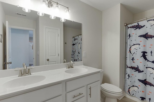 full bath with visible vents, a sink, double vanity, and toilet