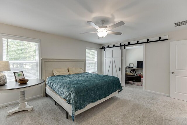 carpeted bedroom with visible vents, a barn door, baseboards, and ceiling fan