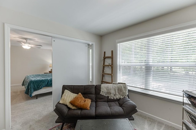 living area with baseboards, a ceiling fan, and carpet