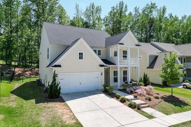 traditional home featuring a front lawn, cooling unit, roof with shingles, an attached garage, and driveway