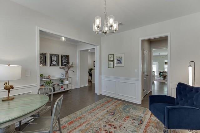dining room featuring dark wood finished floors, a wainscoted wall, and a notable chandelier