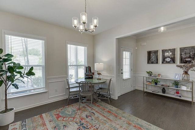 dining room featuring a wainscoted wall, a decorative wall, wood finished floors, and a chandelier