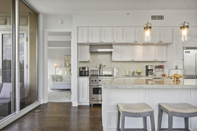 1820 Peachtree St Unit 614, Atlanta, GA 30309 - kitchen with high quality appliances, dark wood-style floors, white cabinetry, light stone counters, and wall chimney range hood