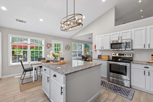 734 Evergreen Dr, Winder, GA 30680 - kitchen with stainless steel appliances, light wood finished floors, a chandelier, a kitchen island, and lofted ceiling