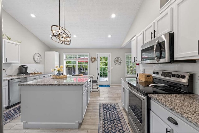734 Evergreen Dr, Winder, GA 30680 - kitchen with stainless steel appliances, lofted ceiling, a kitchen island, decorative backsplash, and a chandelier