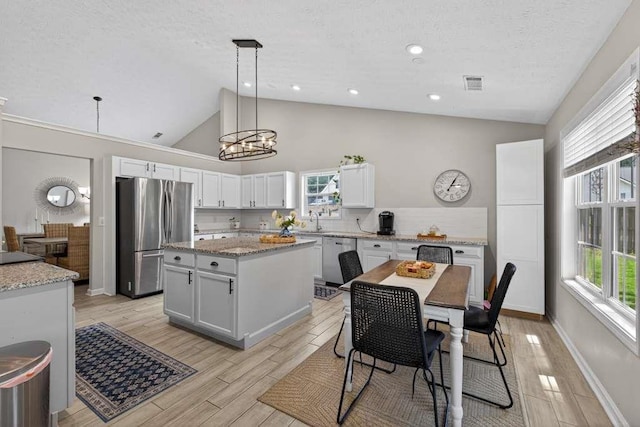 734 Evergreen Dr, Winder, GA 30680 - kitchen featuring appliances with stainless steel finishes, a textured ceiling, a center island, white cabinetry, and hanging light fixtures