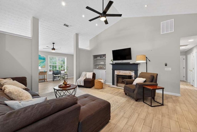 734 Evergreen Dr, Winder, GA 30680 - living area featuring a ceiling fan, high vaulted ceiling, light wood-style flooring, a fireplace, and built in features