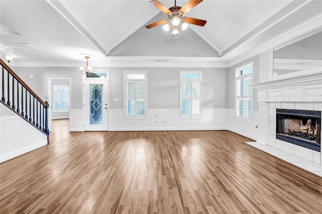 unfurnished living room with lofted ceiling, ornamental molding, and a tiled fireplace