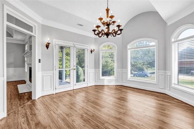 unfurnished living room featuring wood-type flooring, ceiling fan with notable chandelier, vaulted ceiling, and crown molding