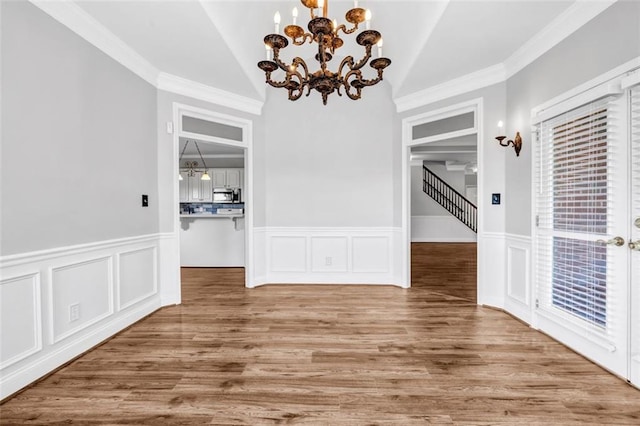 unfurnished dining area with a notable chandelier, vaulted ceiling, crown molding, and wood-type flooring