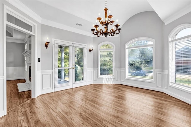 unfurnished dining area featuring a notable chandelier, wood-type flooring, a fireplace, and lofted ceiling