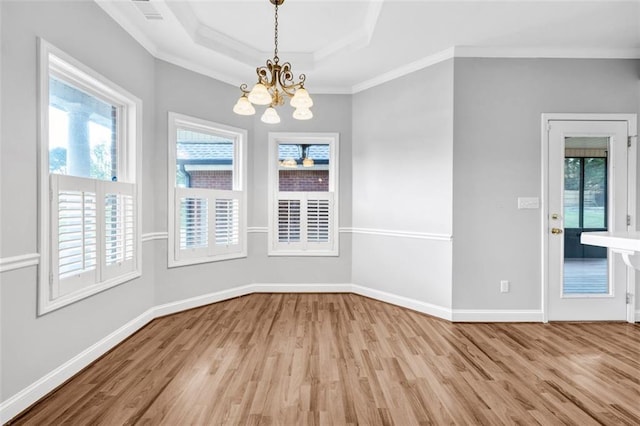 spare room with a raised ceiling, light hardwood / wood-style flooring, plenty of natural light, and crown molding