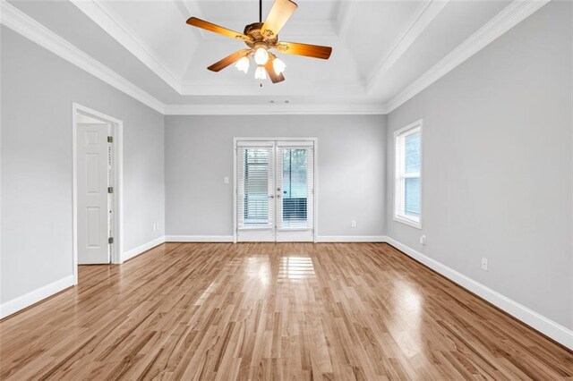 spare room with a raised ceiling, light hardwood / wood-style flooring, plenty of natural light, and crown molding