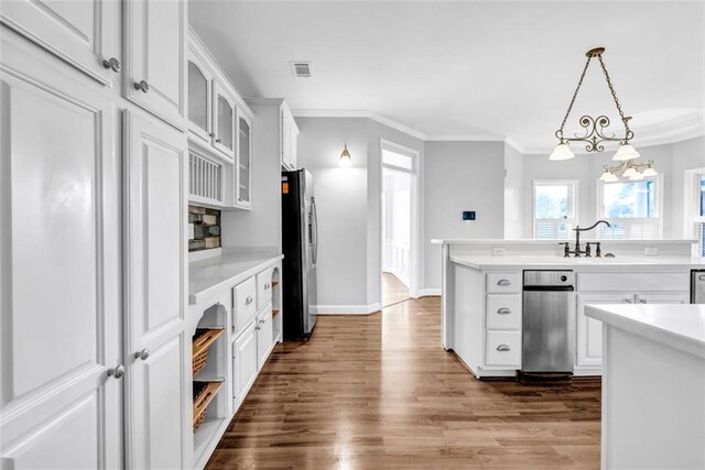 kitchen featuring pendant lighting, white cabinets, appliances with stainless steel finishes, decorative backsplash, and a kitchen island with sink